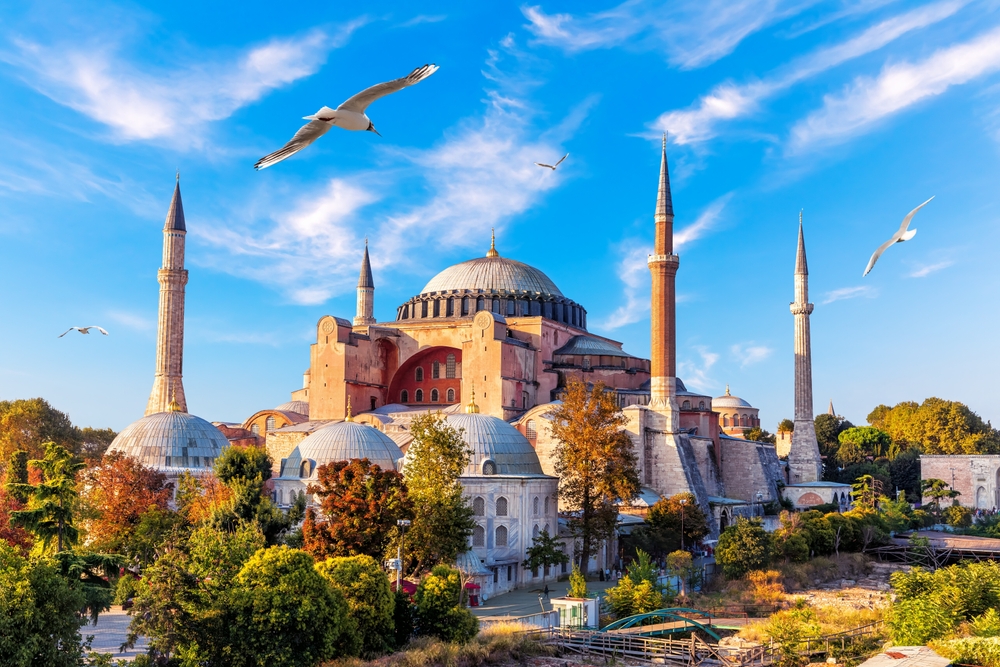 Außenansicht der Hagia Sophia in Istanbul mit großer Kuppel, Minaretten und Besucher-Eingangsbereich bei Sonnenuntergang